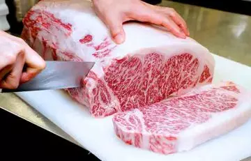 Chef cutting beef that is rich in fat
