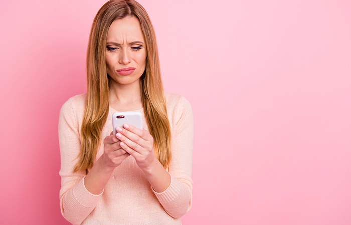 Woman with disgusted expression while reading a text on her phone