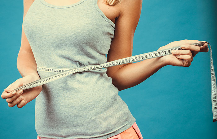 Woman measuring her waist after using abdominal belt
