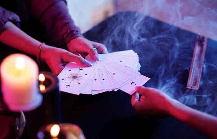 A woman pulling a tarot card from a bunch of tarot cards