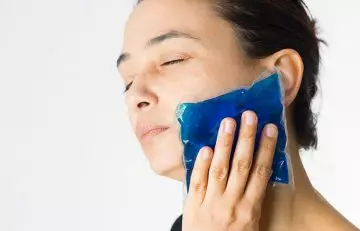 Woman using a cold compress on her face scabs