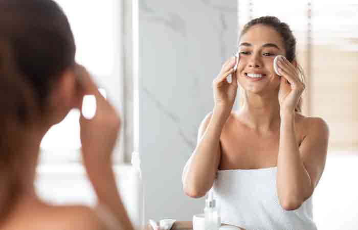 Woman using pumpkin seed oil and cotton pads to remove makeup