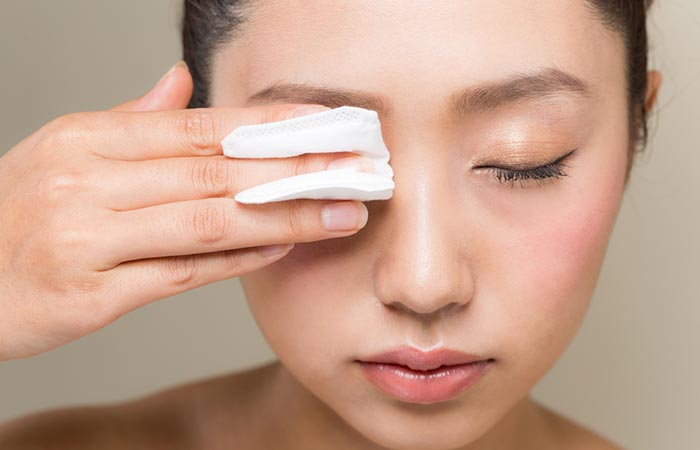 Woman using cotton pad soaked in coconut oil to remove makeup