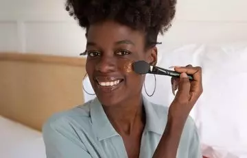 Woman applying liquid foundation on her face