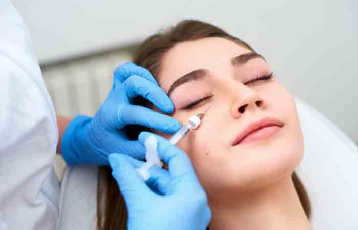 A dermatologist giving a woman an under-eye injection