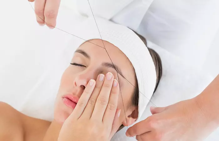 Woman threading another woman's eyebrow