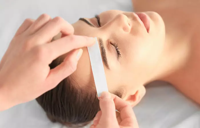 Woman waxing another woman's eyebrow