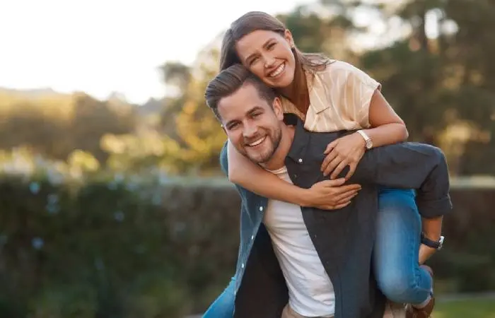 A cute couple piggybacking in the backyard 