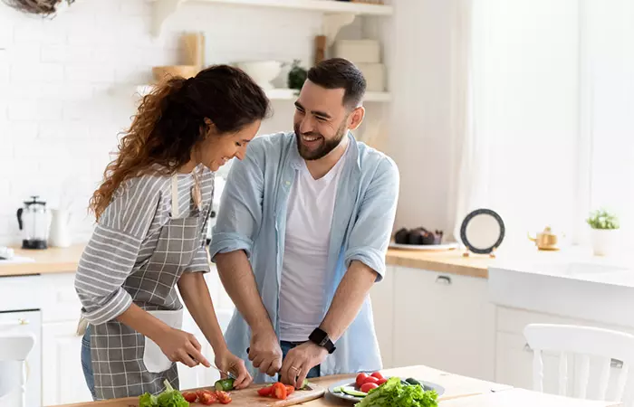 A Pisces man helping a woman cut vegetables in the kitchen