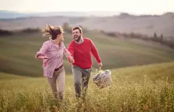 A Taurus-Virgo couple running in a field 