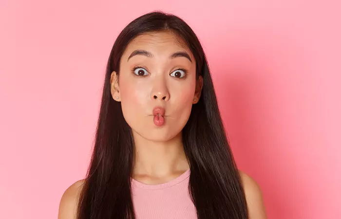Woman demonstrates the fish face exercise for slimming the face