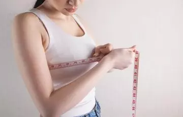 Woman checking her breast size with measuring tape