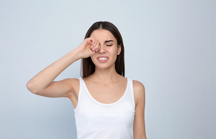 Woman experiencing eye irritation due to sodium methyl cocoyl taurate
