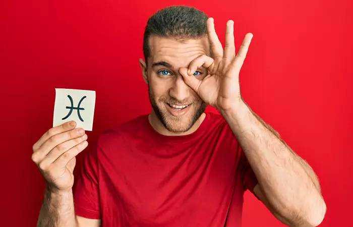 Man holding up the Pisces symbol in one hand