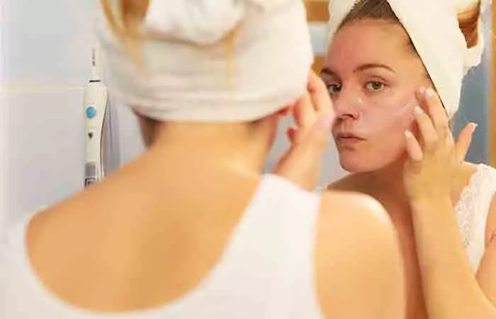 Woman applying Aquaphor on face to moisturize dry skin