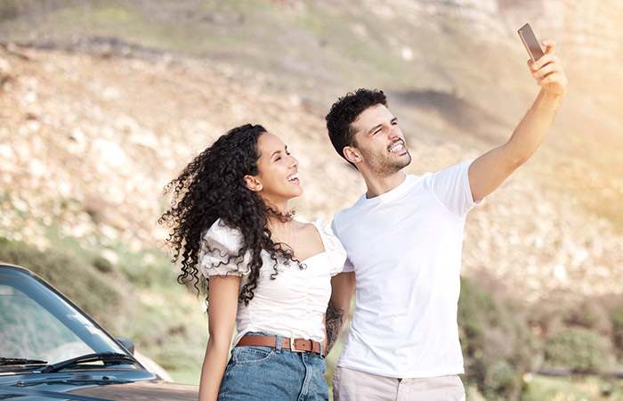 A Pisces man excitedly taking a selfie with a woman