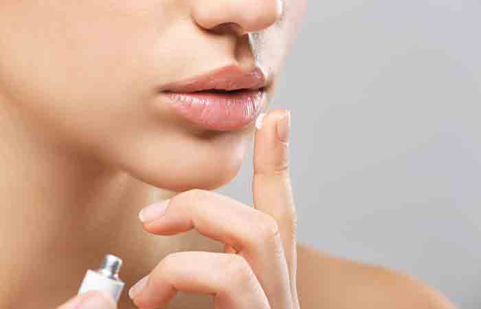 Woman applying Aquaphor on lips to soothe them
