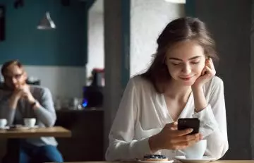 Man falling in love with the woman while she looks at her phone