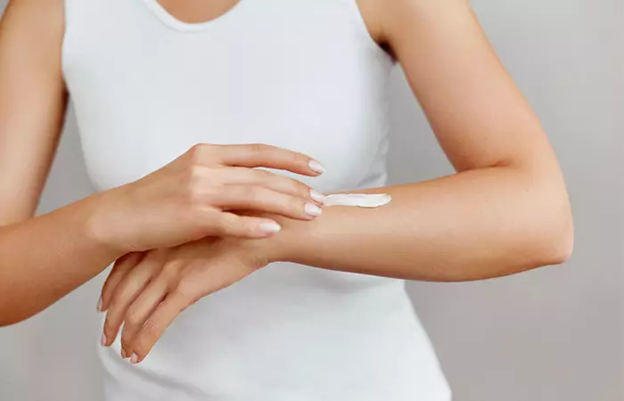 Woman moisturizing her skin as a preventive measure