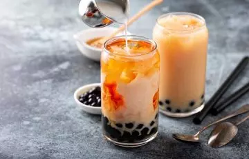 Milk being poured into glasses of boba milk tea