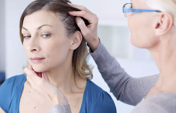 A doctor examines a patient's hairline