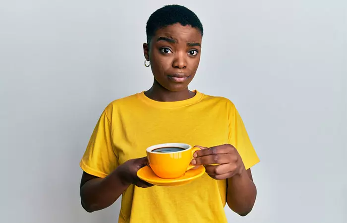 Woman holding a cup of coffee and wondering if it will make her gain weight