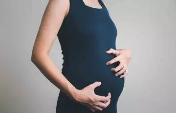 Pregnant woman scratching her belly