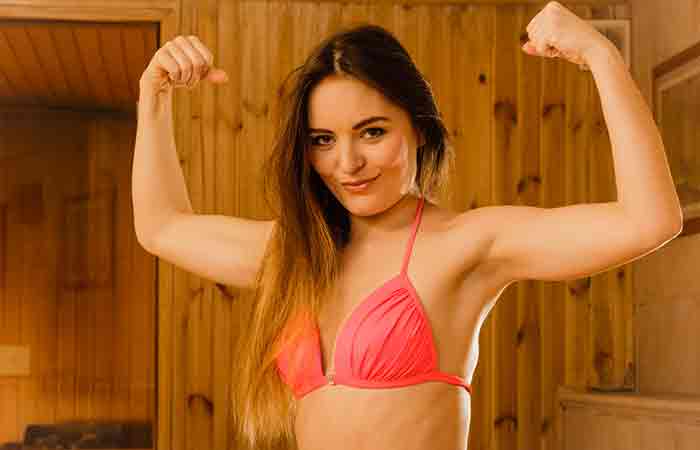 Woman flexing her biceps in a sauna