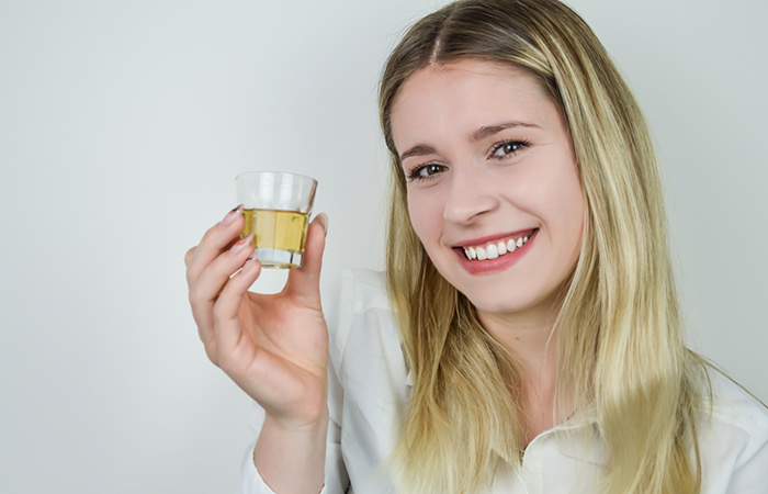 A woman with healthy skin holding a shot of tequila