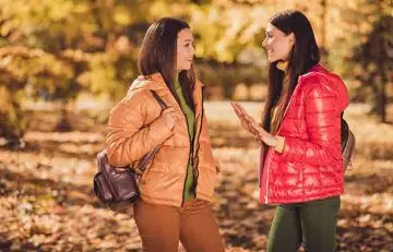 Two women smiling while they talk to uplift their mood. 