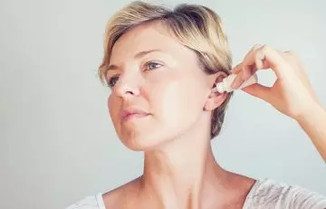 Woman using moisturizing ear drops in ears to keep dryness away