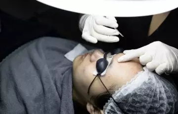 Doctor surgically treating skin abscess on the forehead of a patient