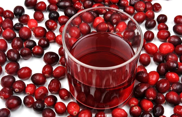 A glass of cranberry juice surrounded by cranberries for a healthy vaginal pH balance