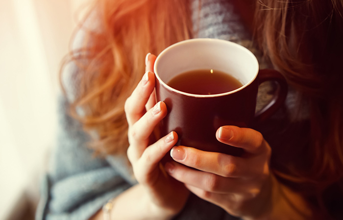 Woman with cup of kratom tea to relieve fatigue