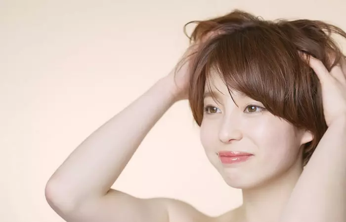 Woman massaging her scalp to strengthen the roots and protect her hairline