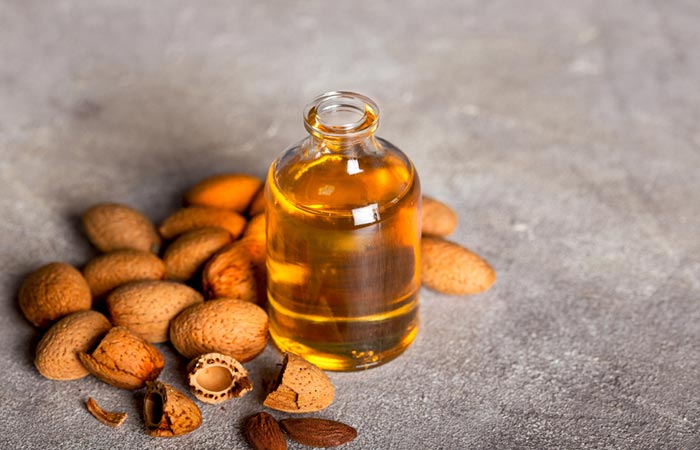 A jar of apricot kernel oil surrounded by apricot kernels