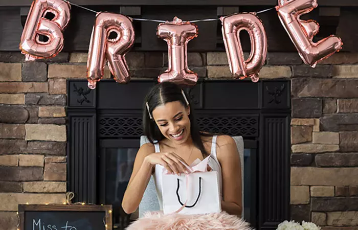 Bride to be opening her bridal shower gifts under the decor