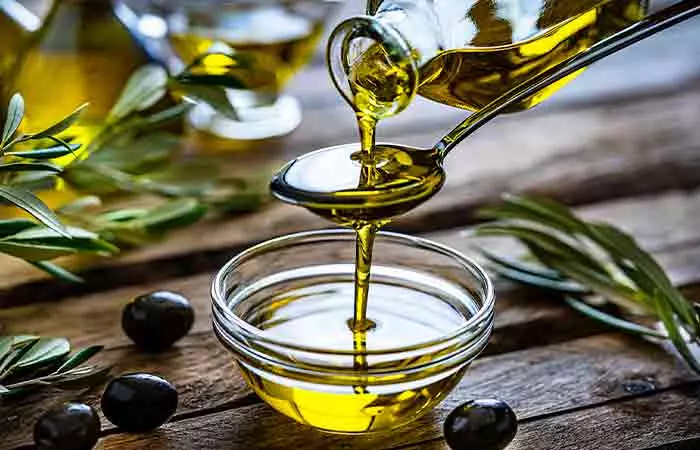 Pouring olive oil from a bottle into a glass bowl