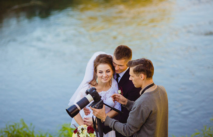 A wedding photographer showing clicked photos to a couple at their wedding