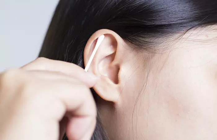 Woman cleaning her ear with a Q-tip 