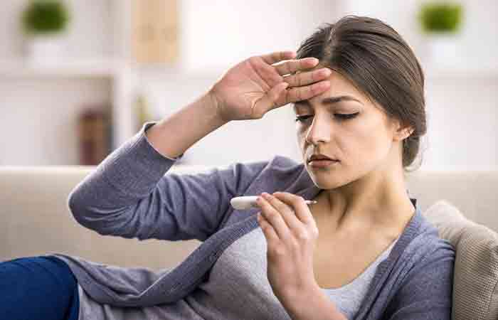 Woman checks her body temperature due to fever and constant headaches which could lead to cyanosis