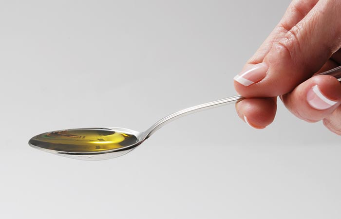 Hand holding a spoonful of carrier oil