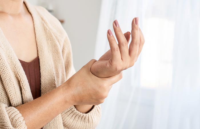 Woman holding her numb hand which is a symptom of ice burn.