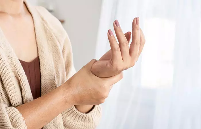 Woman holding her numb hand which is a symptom of ice burn.