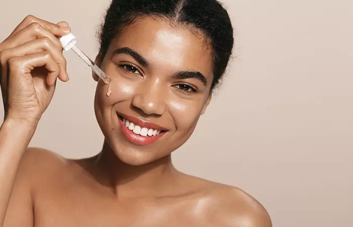 Woman applying liquid collagen on face