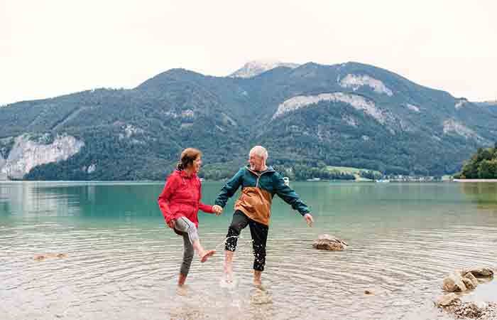 Couple holding hands and splashing water with feet at a mountainside lake