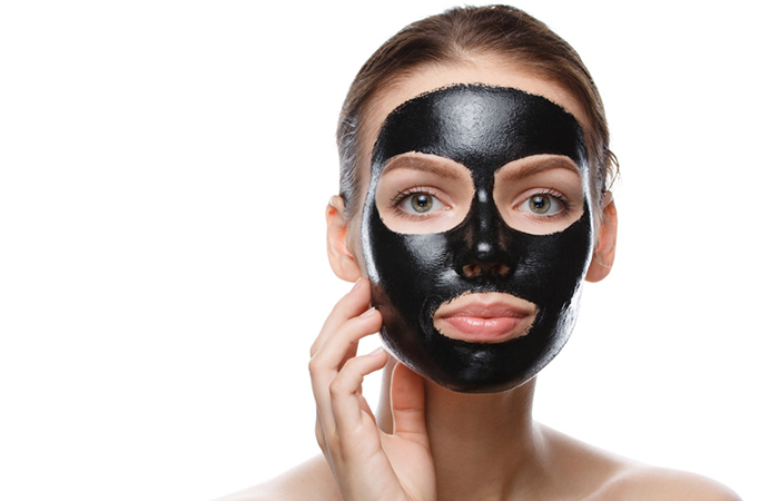 Woman uses a charcoal mask to remove deep blackheads from her face