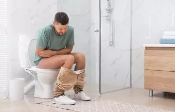 Man sitting uncomfortably on the toilet due to constipation