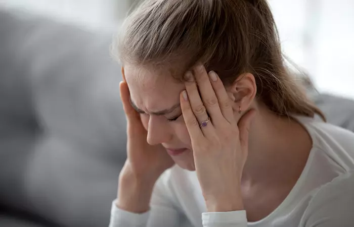 Woman touching her head due to headache as a side effect of asparagus