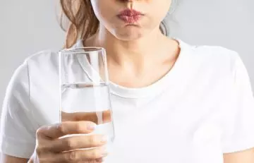 Woman gargling with salt wtaer to treat gum boil